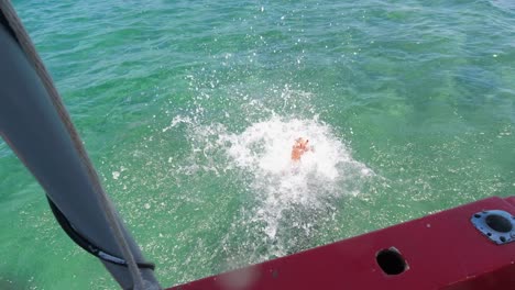 mujer morena trenzada se desliza del barco al agua con máscara, snorkel