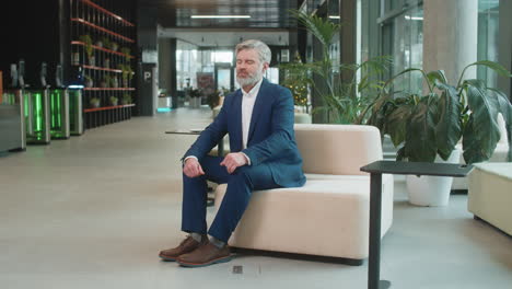 caucasian businessman taking break leaning on couch after working celebrating success at hotel lobby