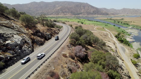 aerial view of white suv driving along hillside road towards desert landscape in california