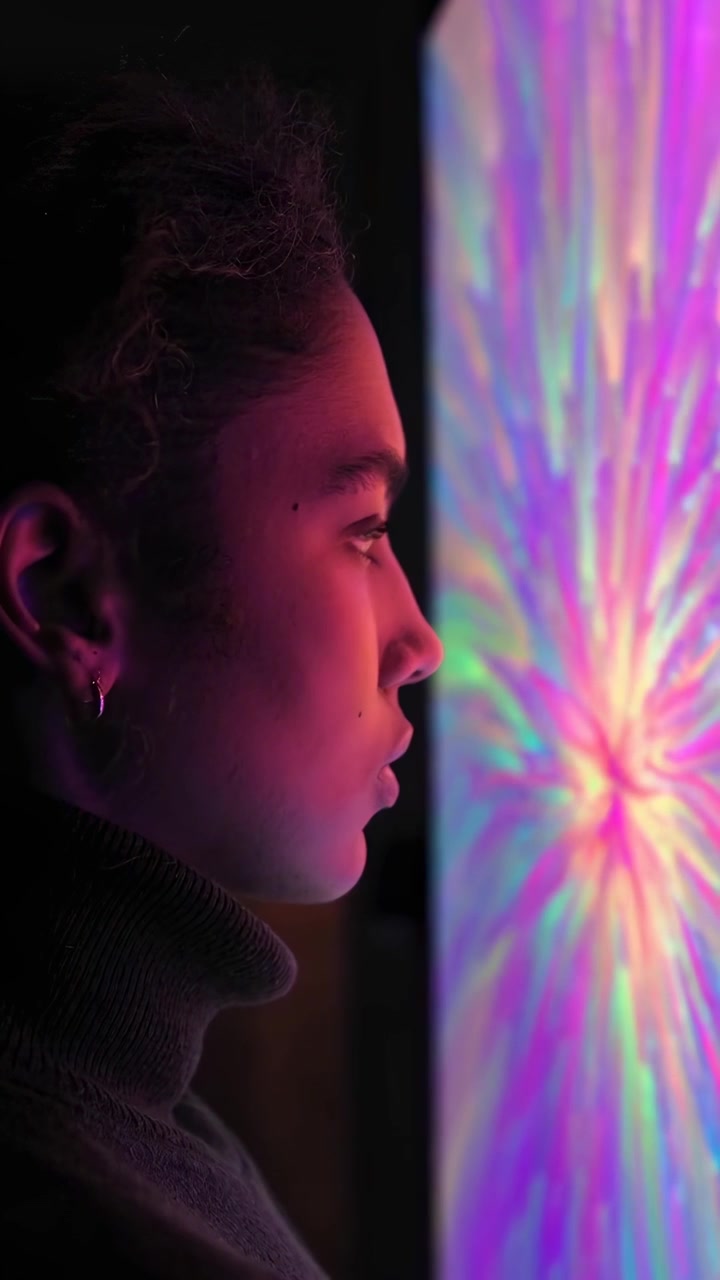 Young Woman Mesmerized by Abstract Colorful Glowing Screen