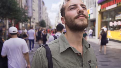 young man walking on the modern city street looks around.