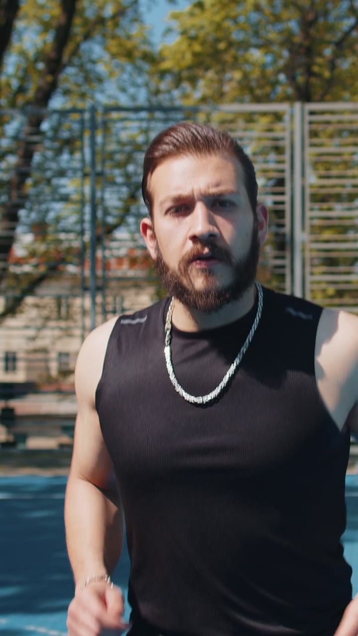 Atletisk sportsmand jogger bruger smart watch og tjekker puls og rute, mens han løber på en basketballbane