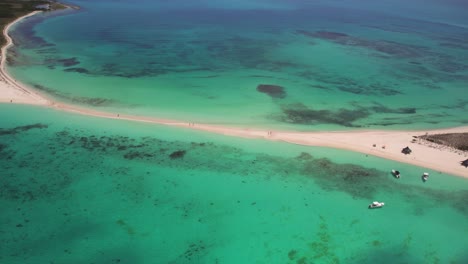 Cayo-de-agua-with-crystal-clear-waters-and-people-on-the-beach-at-daylight,-aerial-view