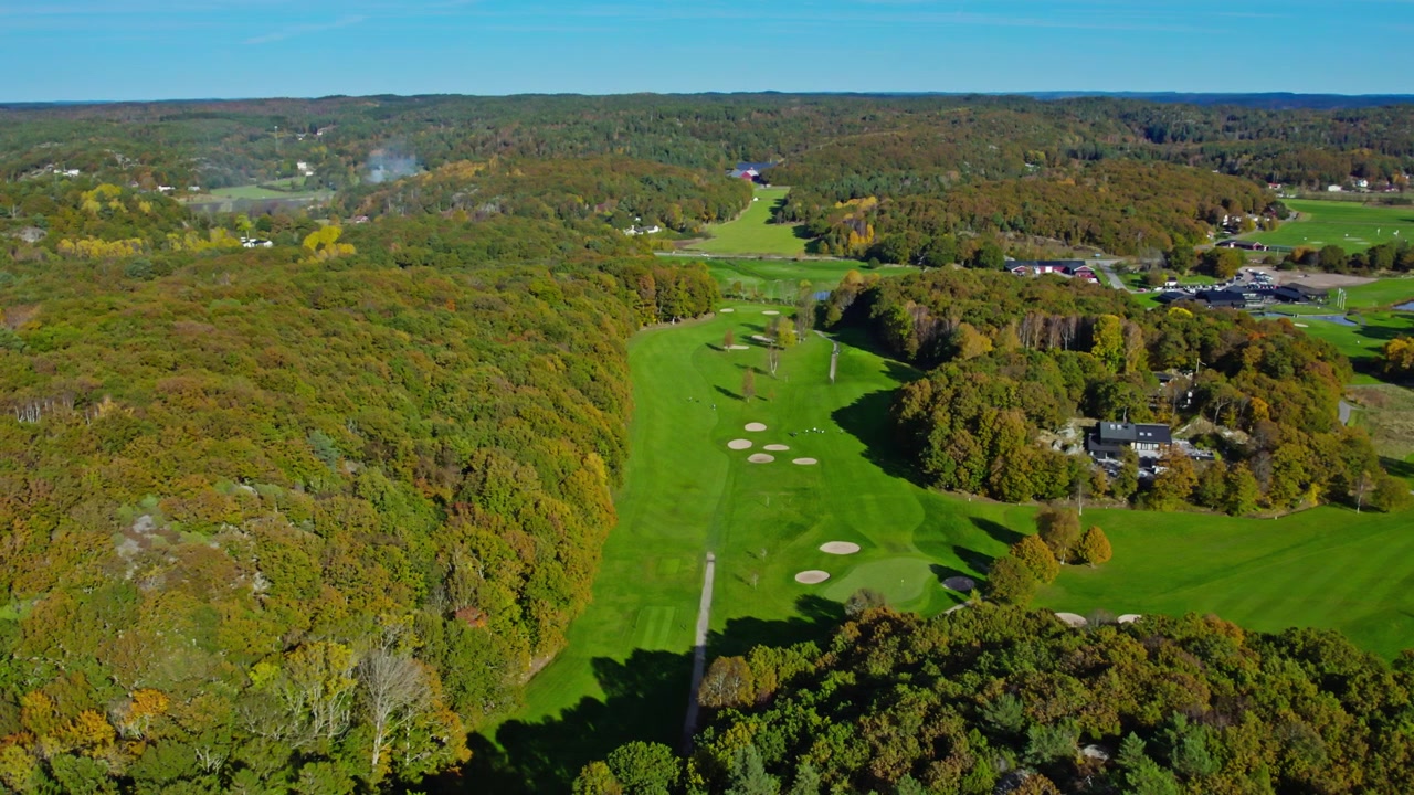 Luftaufnahme mit Drohne vom Kungsbacka Golfclub mit Fairways, Grüns, Sandbunkern, farbenprächtigem Herbstwald und sanfter Hügellandschaft in Halland