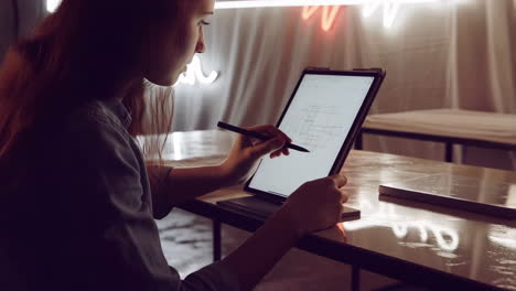 creative woman designing on a tablet with neon lights in the background