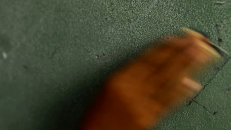 hand of schoolboy rubbing chalkboard with duster in classroom