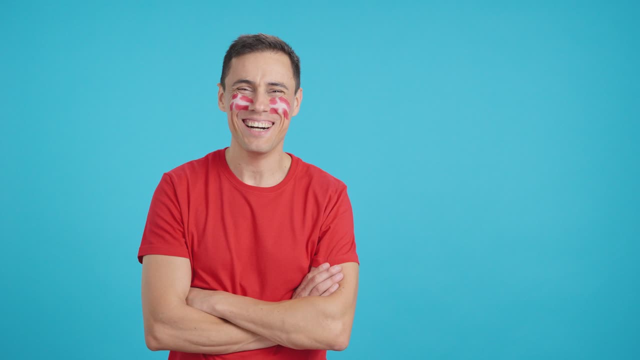 Man standing with danish flag painted on face smiling