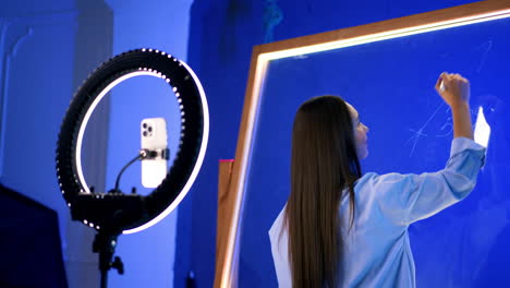 live online teaching session. instructor demonstrates concepts by writing on a glass board while using a ring light for better visibility