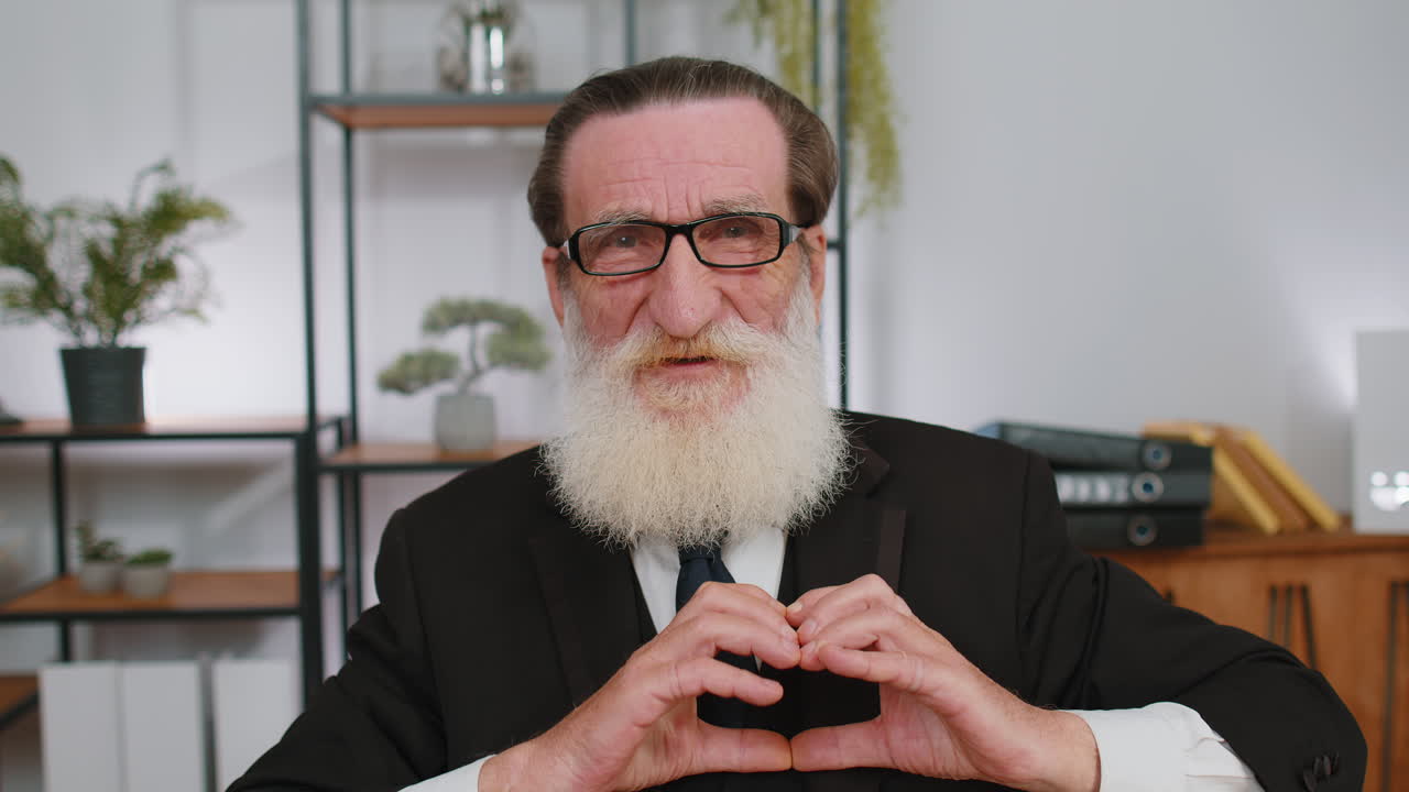 고위 사업가는 사랑의 상징을 만 ⁇ 니다. 카메라에 심장 기호를 보여주고,  ⁇ 만적인 감정을 표현합니다.