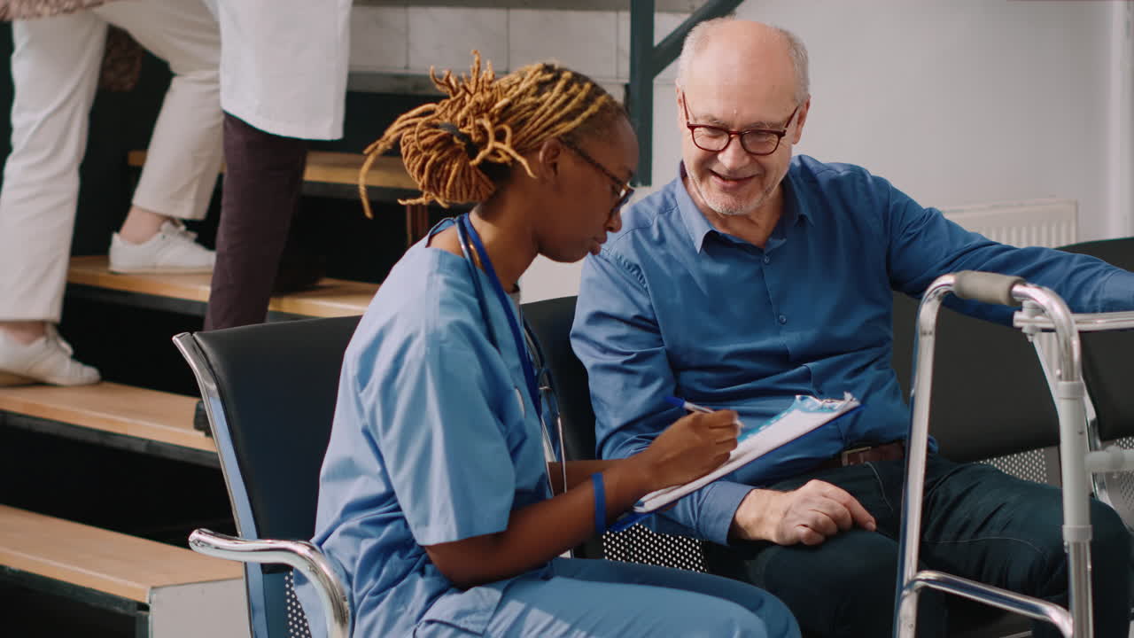 Medical assistant consulting elderly man with walking frame