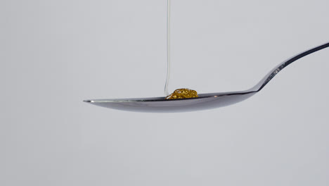 sweet golden honey dripping, healthy liquid nectar flowing onto a metal spoon and dropping down