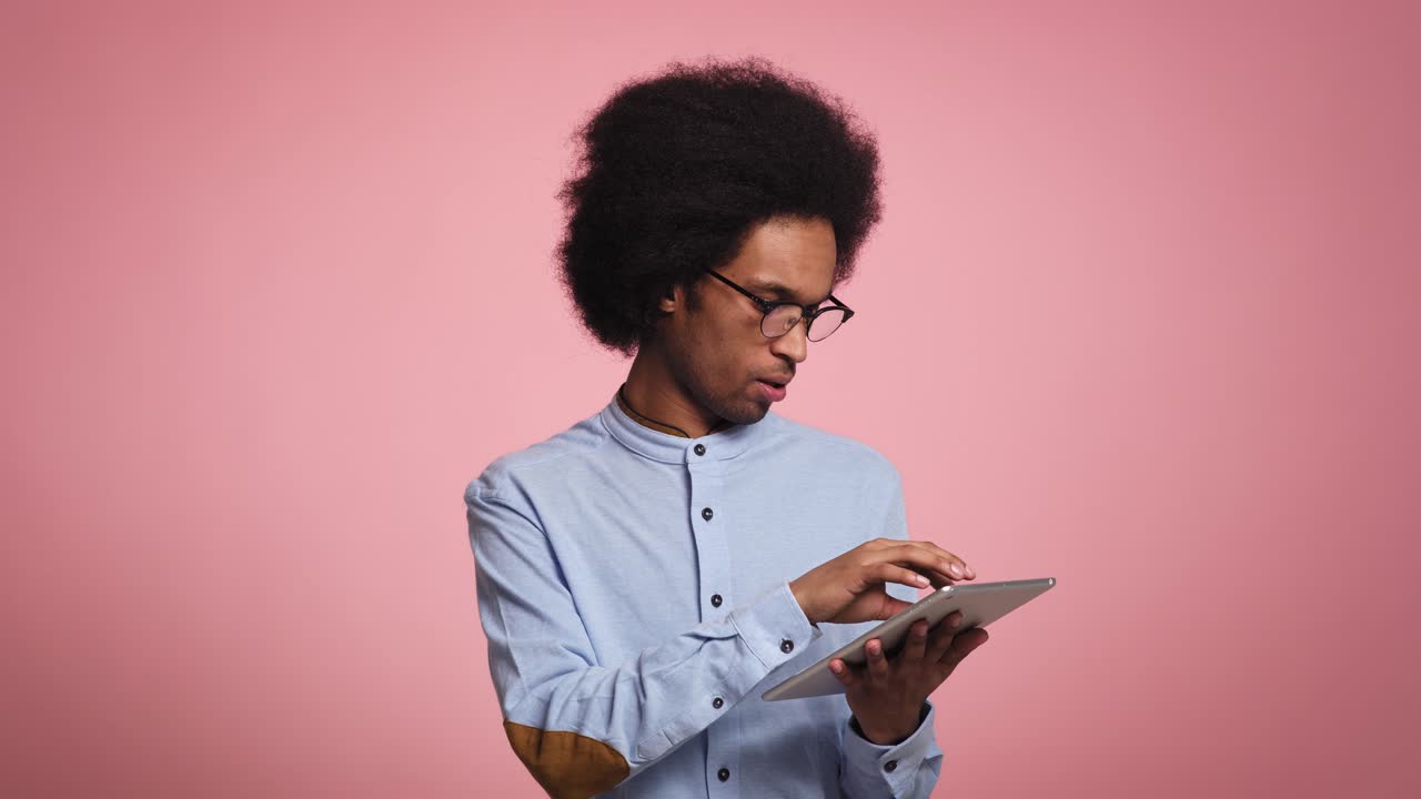 Young African man uses a digital tablet in studio shot