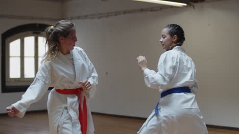 tiro de seguimiento de chicas serias en kimonos peleando en el gimnasio