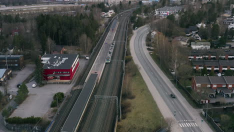 a drone passes over the train tracks and roads in a scandinavian city tilting down from the orange skyline to the grey pathways of trains and cars