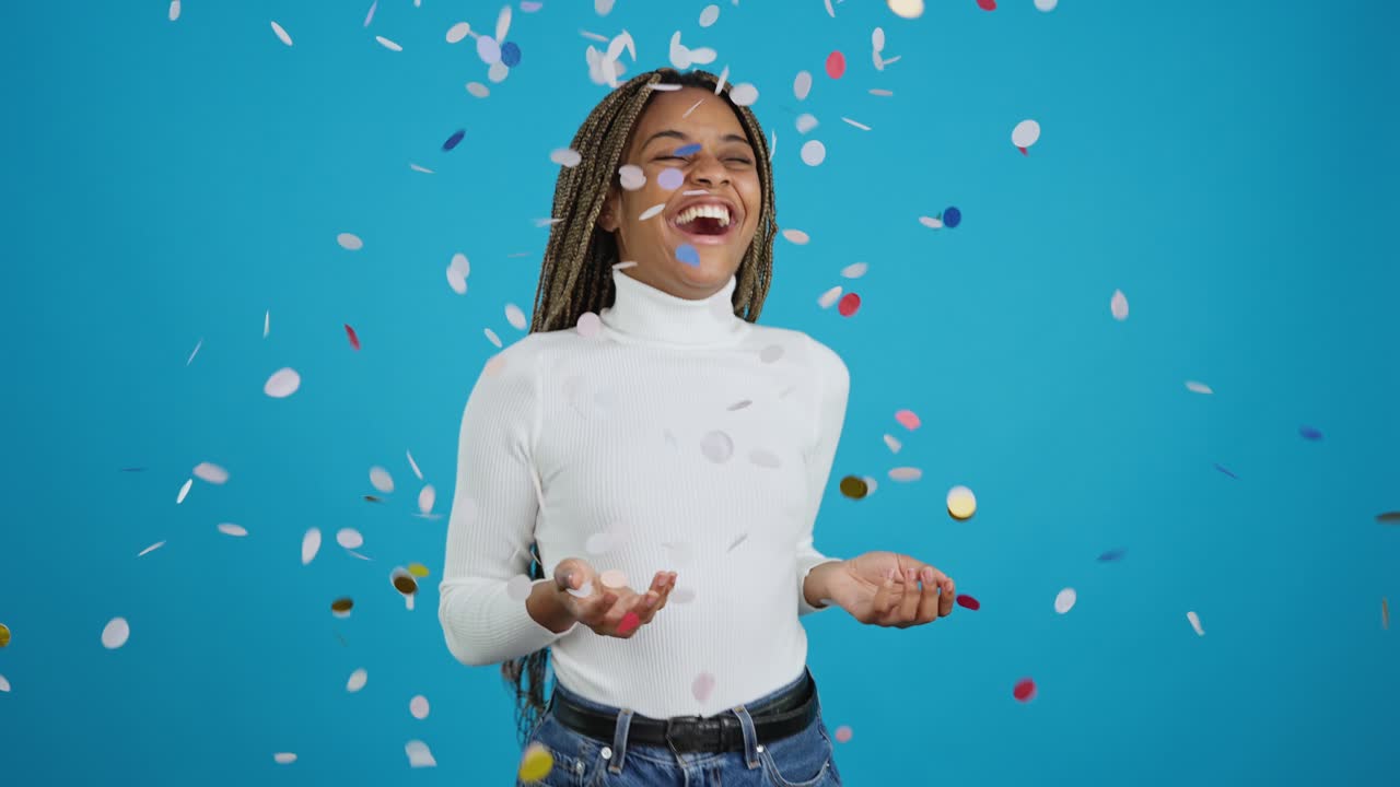 A joyful woman celebrates with colorful confetti falling around her