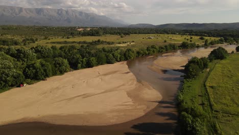 Río-Seco-Con-Verdes-Orillas-Y-Montañas-De-Fondo,-Córdoba,-Argentina