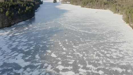 people ice skating on a frozen lake - 4k drone aerial overview