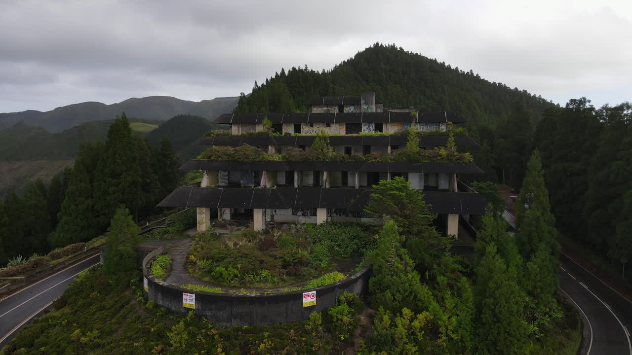 Abandoned hotel stands among vibrant greenery in Sao Miguel, Azores, showcasing nature's reclaiming of human structures