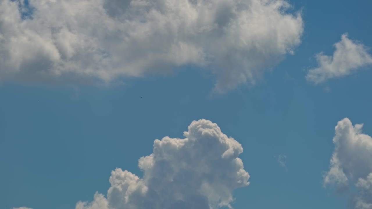 Bright clouds drift across a blue sky on a sunny day