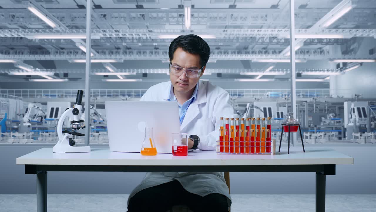 연구실에서 현미경과 시험관으로 테이블에서 일하는 동안 노트북으로 타이핑하는 아시아인 과학자.