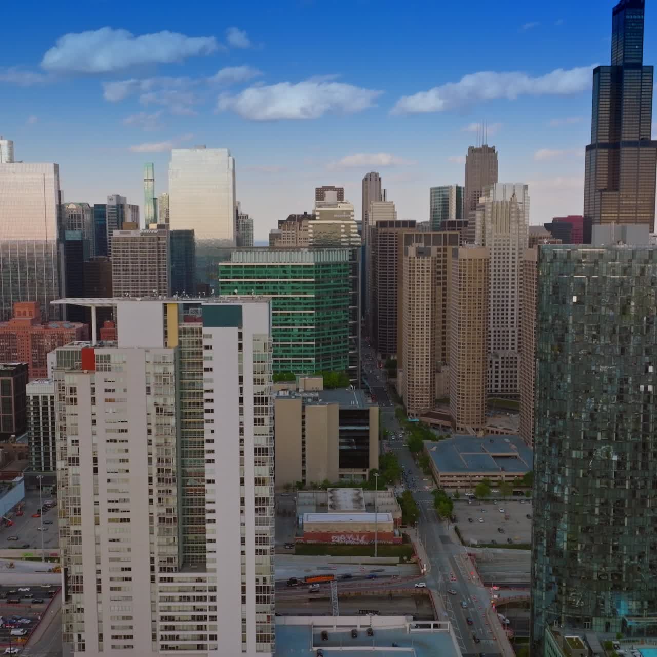 Chicago city with its busy traffic at daytime. Drone footage over the beautiful buildings at the backdrop of blue sky