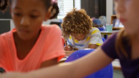 vista frontal de un escolar afroamericano estudiando en el aula 4k