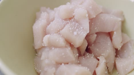 seasoning some chopped chicken meat with salt and pepper