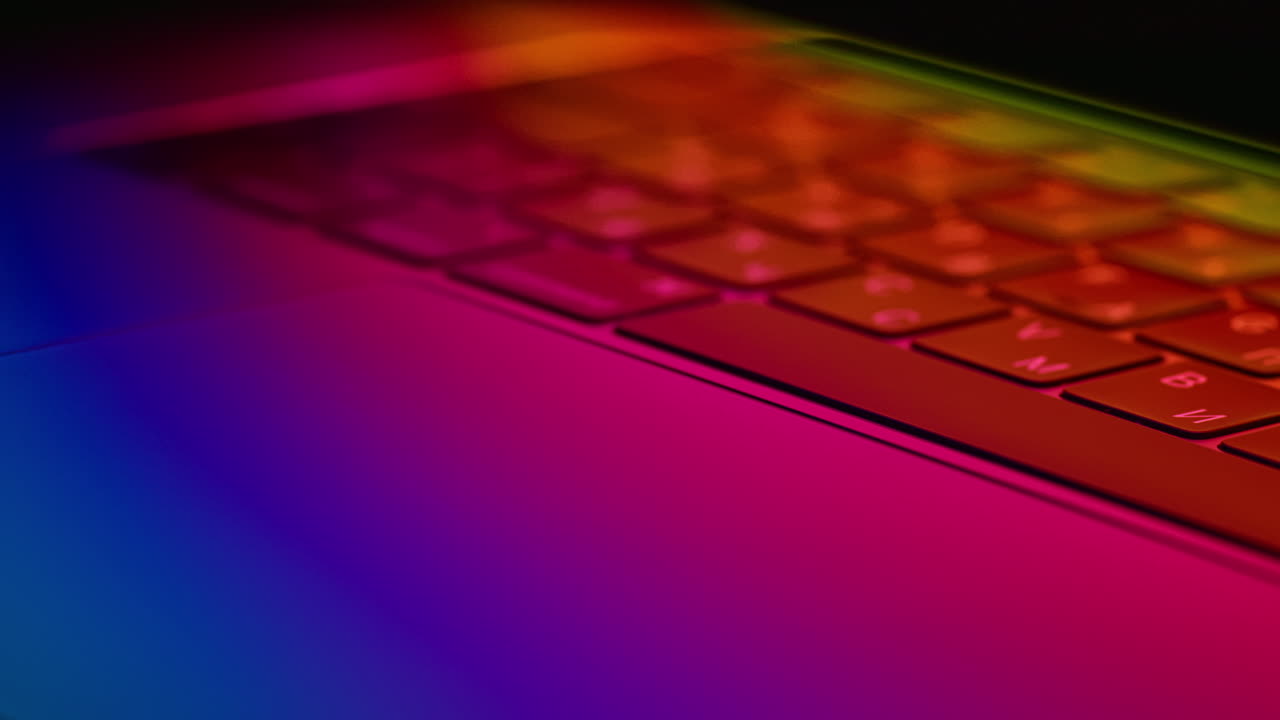 un primer plano revela un teclado de portátil futurista brillante iluminado con luces de neón