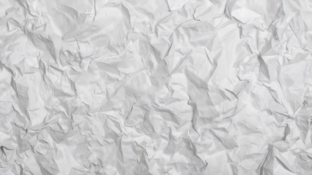 Panning camera over one crumpled white paper sheet to reveal smoother right margin, close-up
