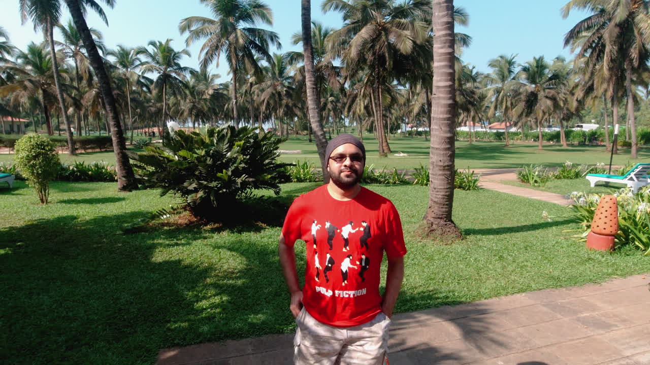 Indiase man maakt een ontspannen wandeling in Candolim Beach Resort Goa, genietend van slow motion momenten