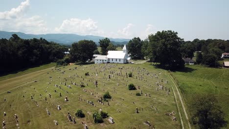 beautiful setting, aerial over trees flying toward church chapel with mountain backdrop