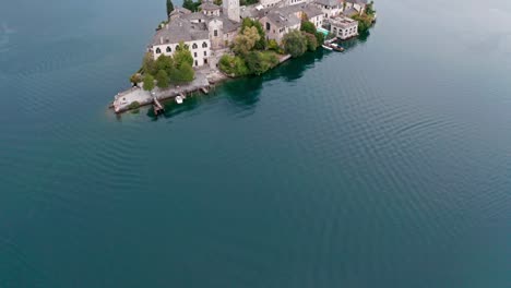 isola san giulio on lake orta in italy, showcasing historic buildings and calm waters, green hills in the background, aerial view