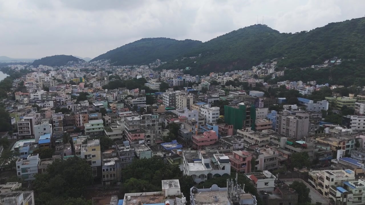 Una suggestiva veduta aerea di Vijayawada, dove la moderna scena urbana contrasta con la collina naturale incontaminata sullo sfondo.