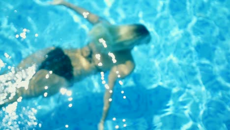 mujer nada bajo el agua en la piscina