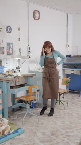 woman takes a phone call in her craft workshop