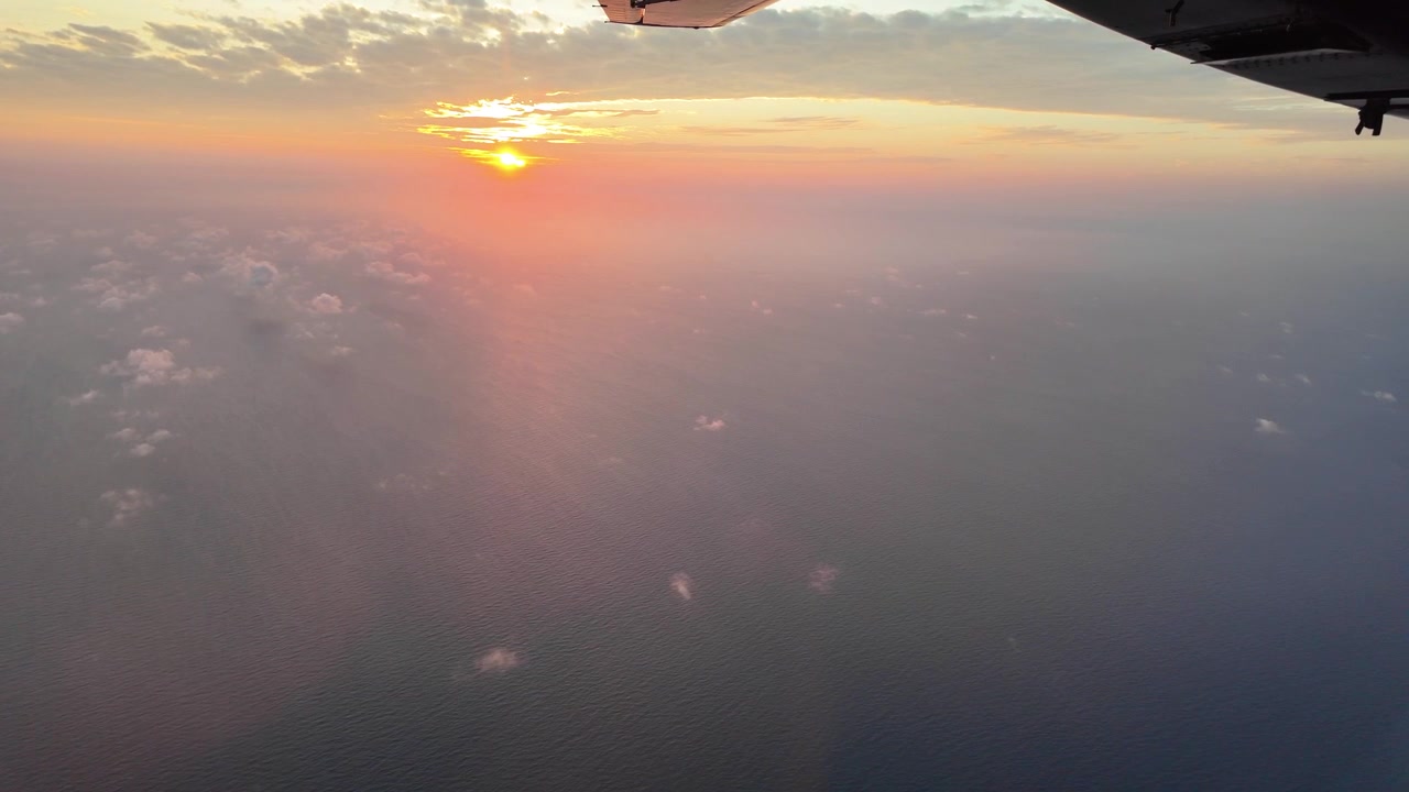 Flyvning over havet i den gyldne time fanget indefra et lille fly, mens solen går ned i horisonten