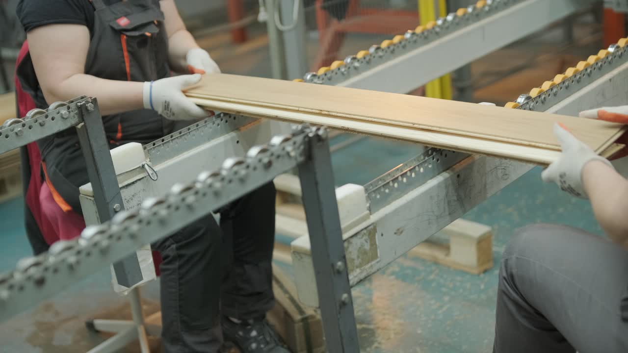Arbeiter sortieren Holzplanken auf einem Förderband in einer Fabrik