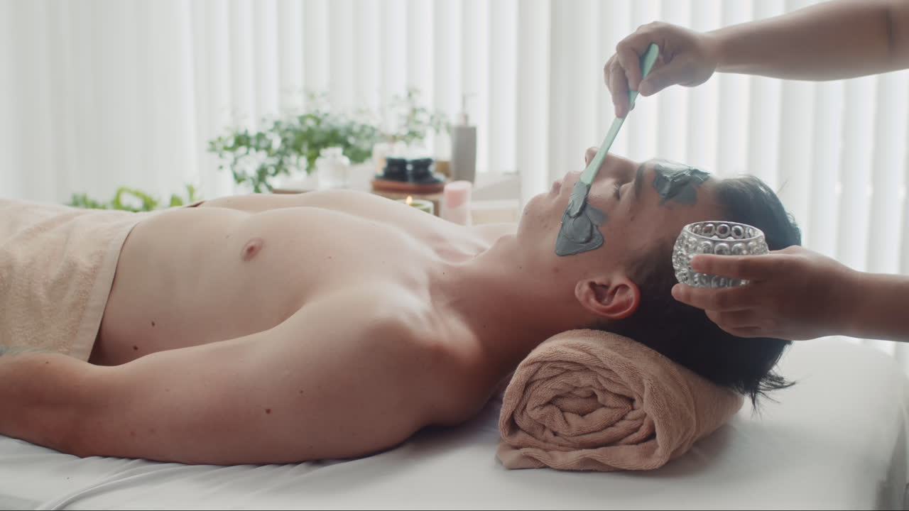 Beauty Specialist Applying Clay on Face of Man