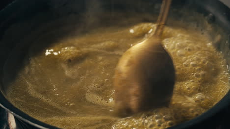 green boiling sauce texture close-up macro. cooking green curry with wooden spoon at home.