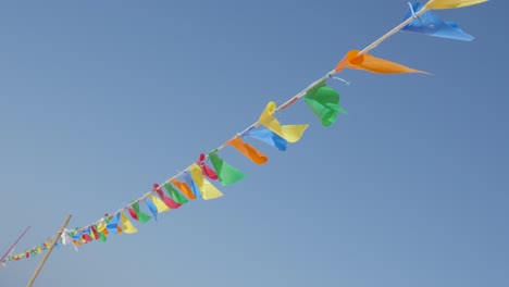 slow motion colorful pennant banner crowd control rope against blue sky