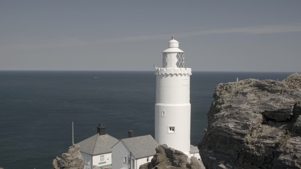 Smooth pan from left to right reveals white lighthouse and vast blue seascape