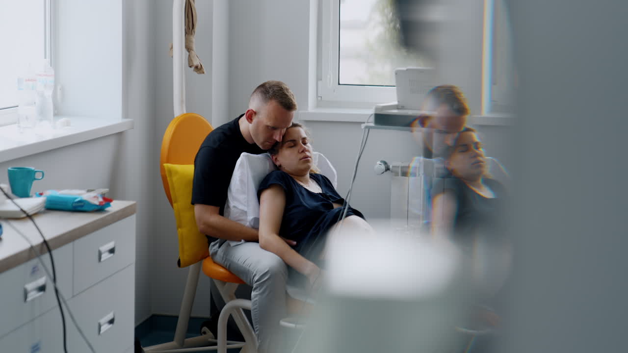 Man sits holding in arms his pregnant wife. Caucasian couple delivering a baby in hospital.