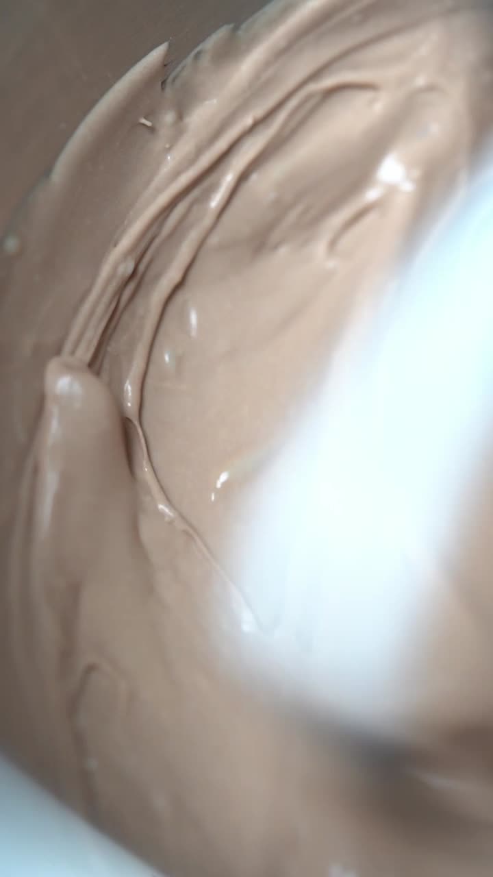 View of creamy chocolate batter being mixed smoothly creating delicious texture, insert shot