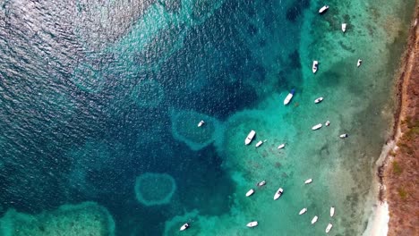 DRONE-BEACH-TAKE-OF-BOATS-IN-CRYSTAL-CLEAR-BLUE-WATER-BEACH