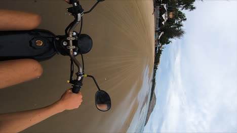 person riding motorbike on sandy beach of vietnam, vertical pov shot