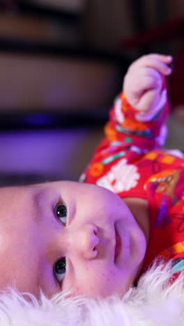 cheerful smiling baby lies on his back tossing his arms and legs. adorable healthy little child close up. blurred backdrop. vertical video