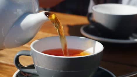close-up-of-pouring-tea-from-a-jug-to-a-cup