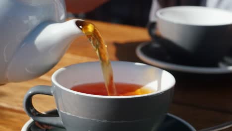 close up of pouring tea from a jug to a cup