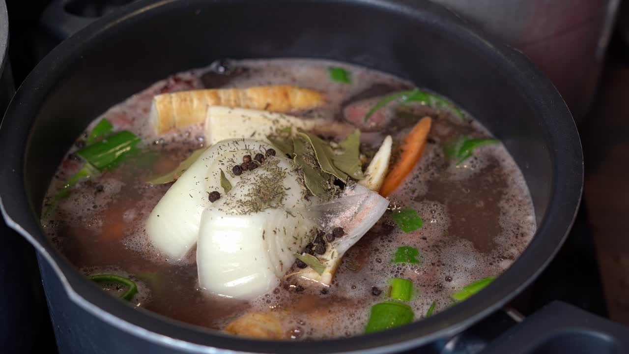 olla de caldo de hueso, con verduras y condimentos, hirviendo lentamente en una olla grande