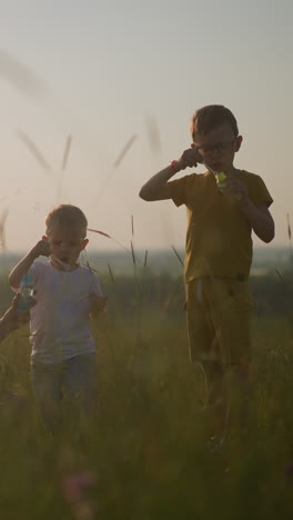 a tranquil moment in a grassy field, where a woman sits while a little boy bends beside her, and another boy stands close. they joyfully blow bubbles into the air, basking in the warm glow of sun